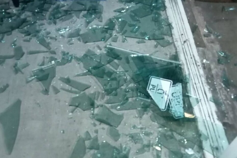 glass shards cover a concrete floor. The edge of the doorframe is visible on the right side.